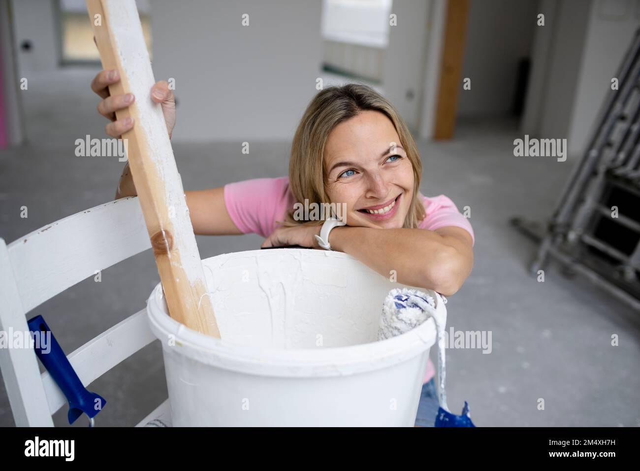 Felice giorno della donna sognando appoggiarsi sul secchio di vernice in appartamento Foto Stock