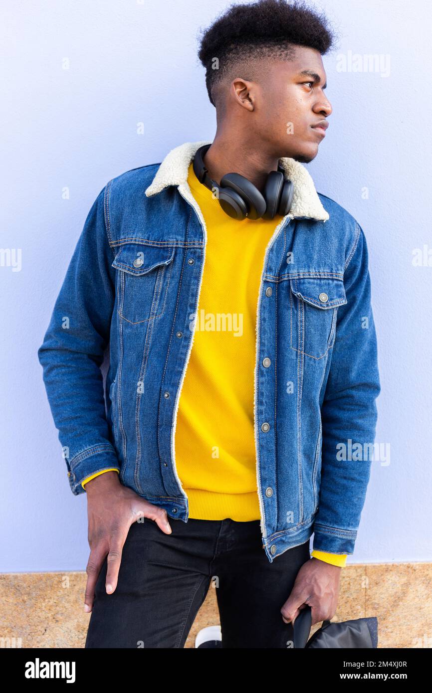 Giovane uomo che indossa una giacca in denim davanti alla parete Foto Stock