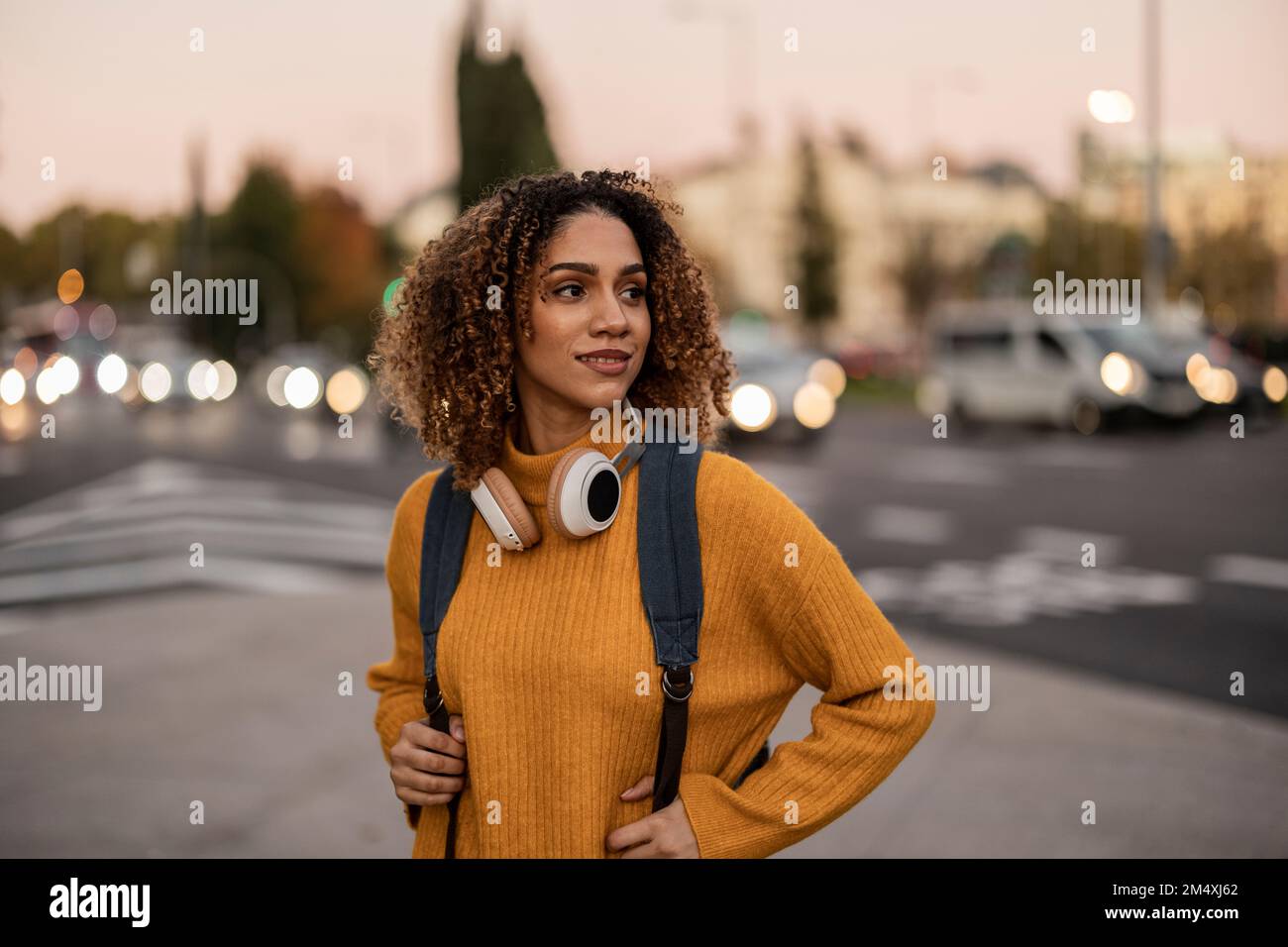Bella giovane donna con zaino e cuffie wireless Foto Stock