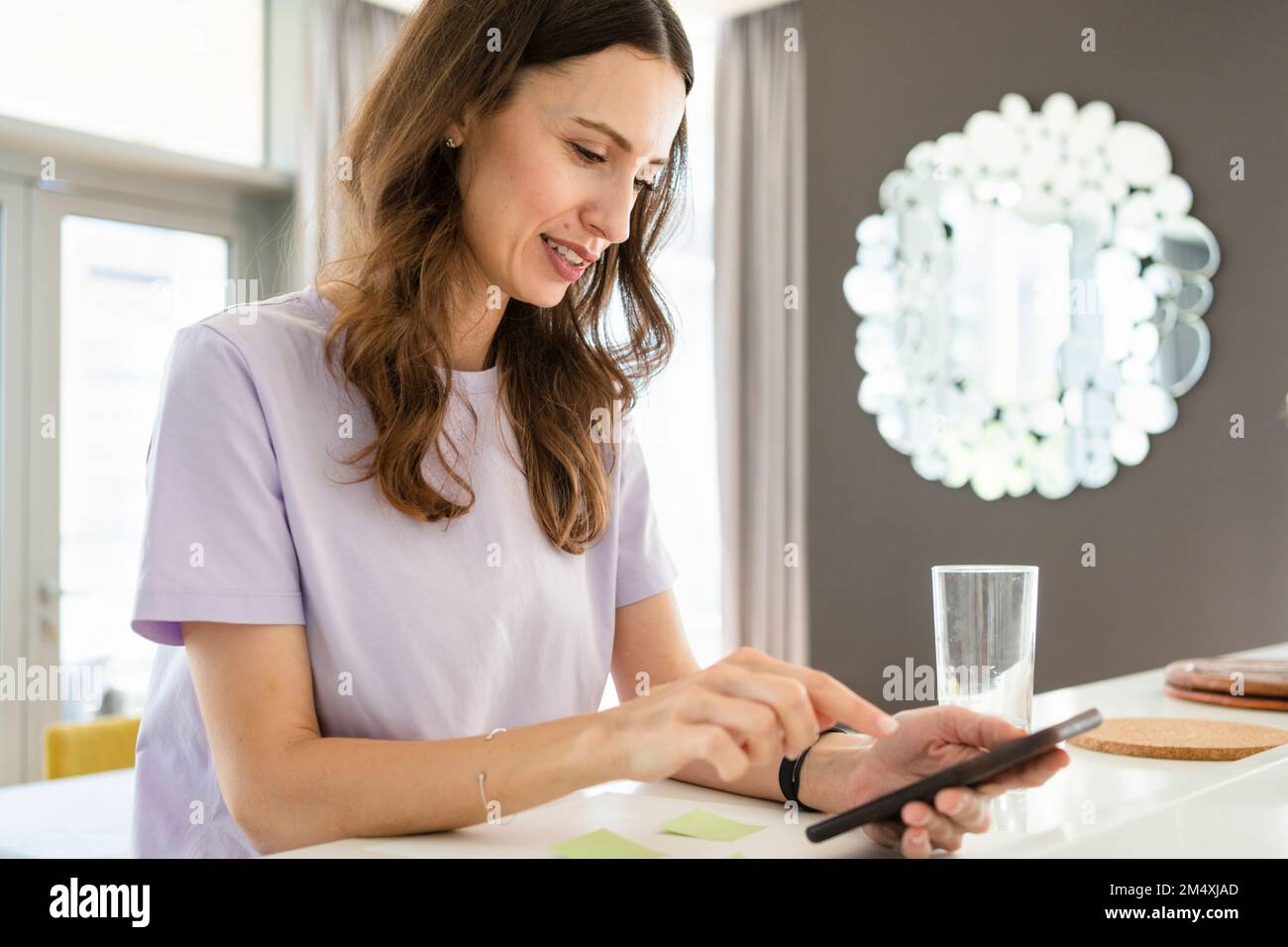 Freelance che utilizza lo smartphone in salotto Foto Stock