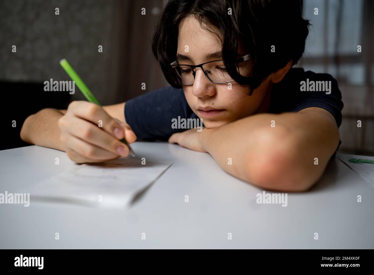 Ragazzo che scrive con la penna sulla carta a casa Foto Stock