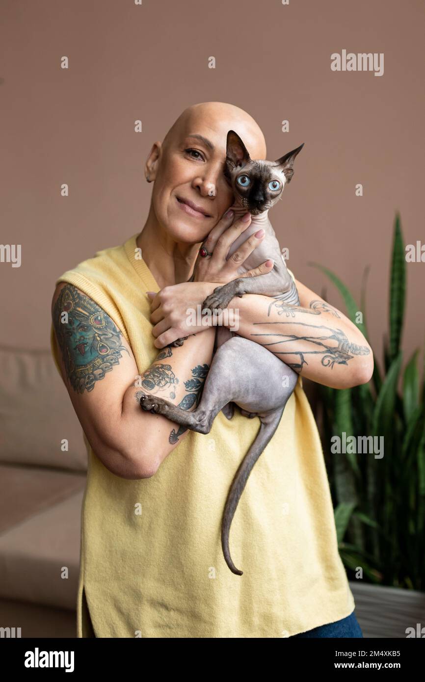 Donna senza capelli che tiene in braccio il gatto Sphynx Foto Stock