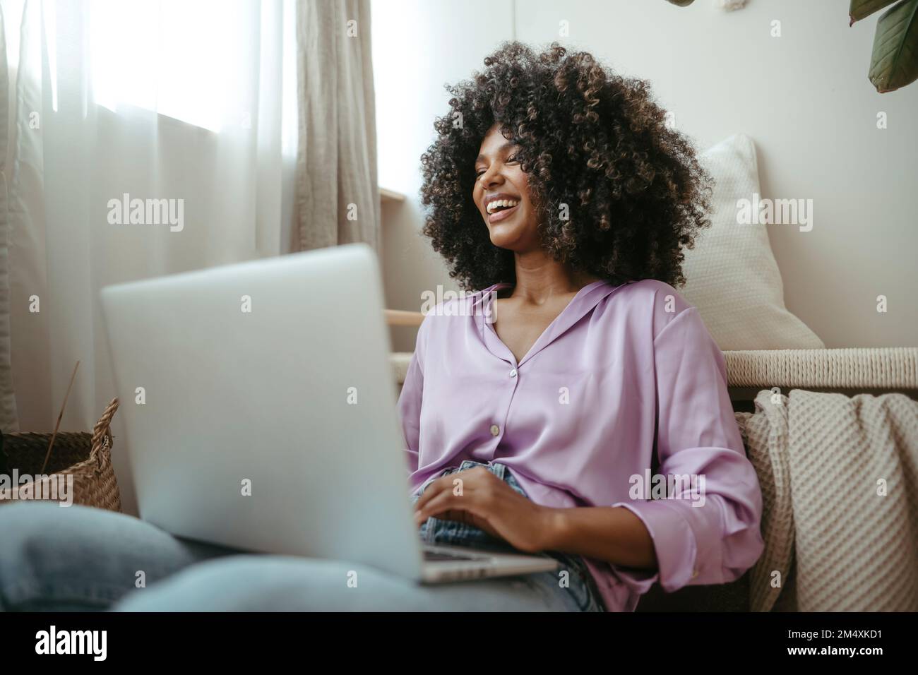 Giovane donna allegra con notebook in soggiorno Foto Stock