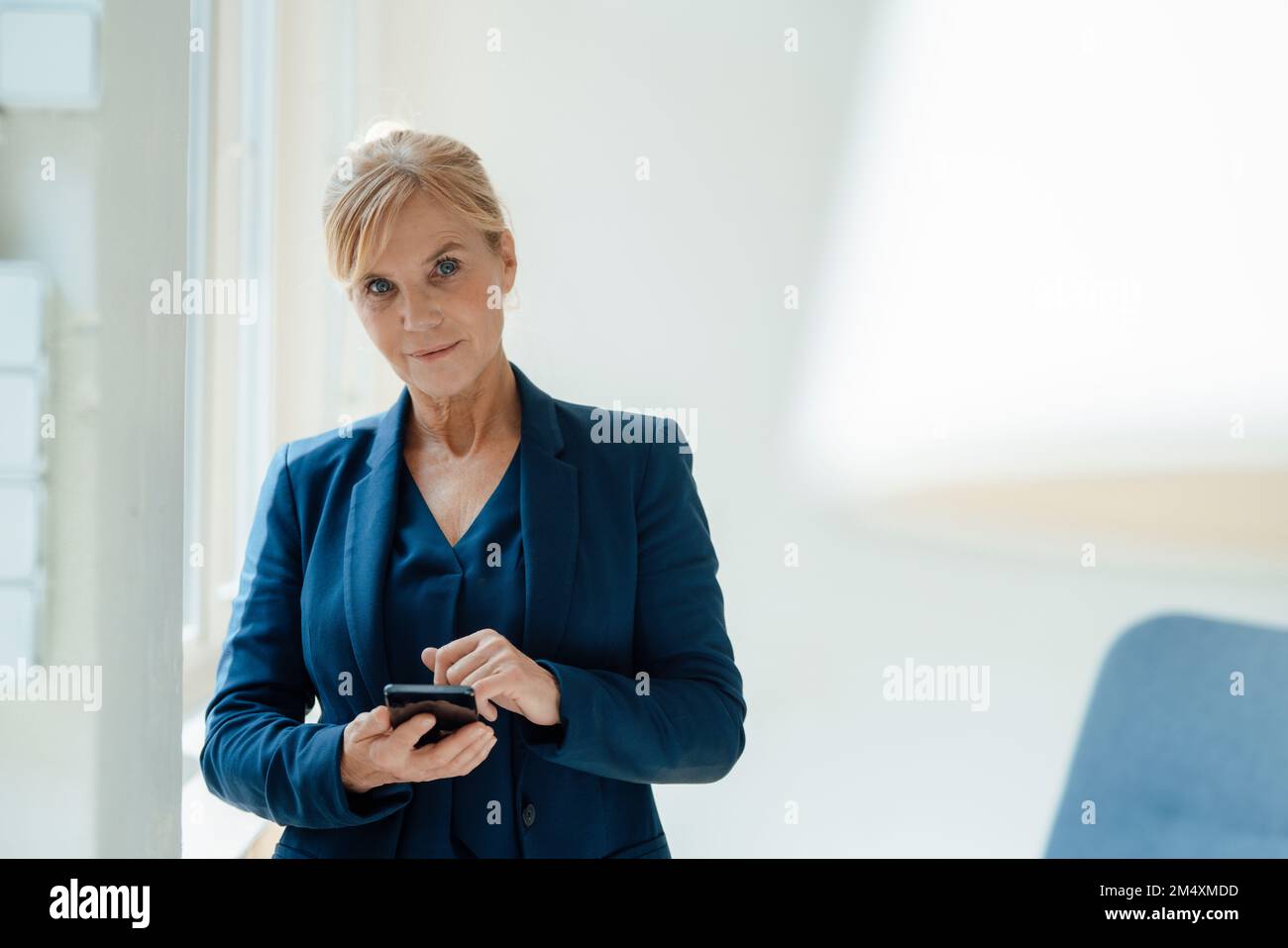 Donna d'affari con smartphone sul posto di lavoro Foto Stock