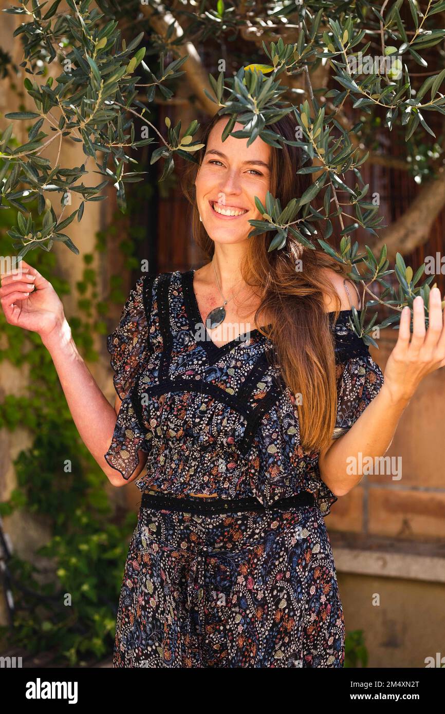 Donna felice in piedi in giardino sotto il ramo Foto Stock