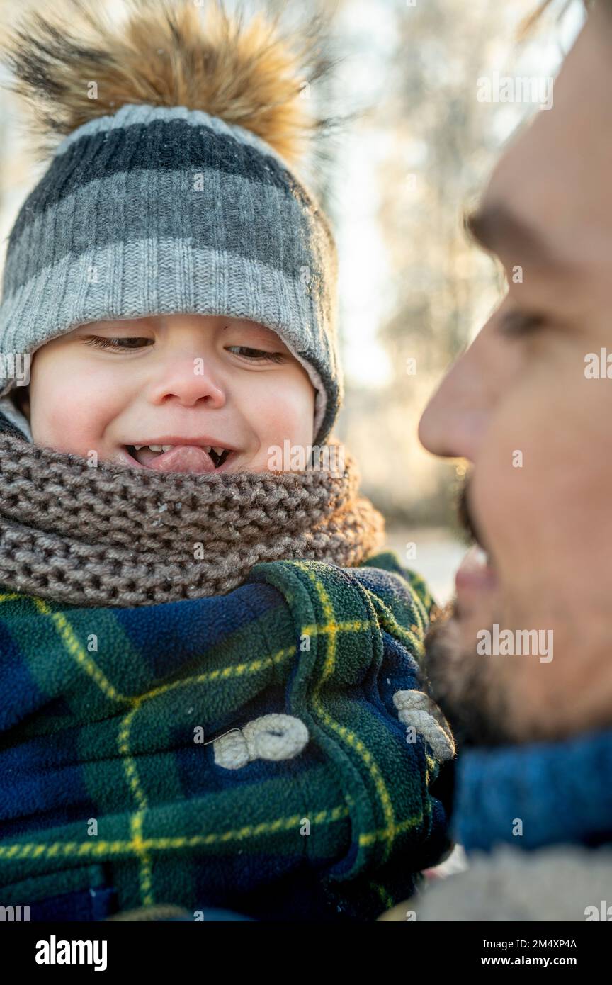Uomo che guarda il figlio che si stacca la lingua in inverno Foto Stock