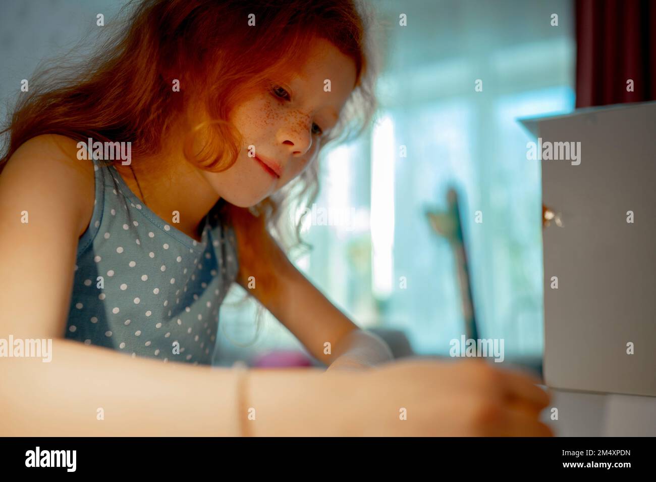 La ragazza di Redhead che fa i compiti a casa Foto Stock