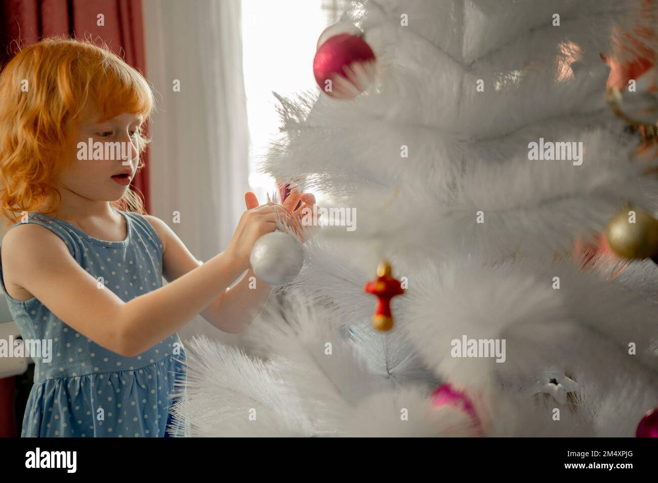 Red head ragazza decorazione artificiale albero di Natale a casa Foto Stock