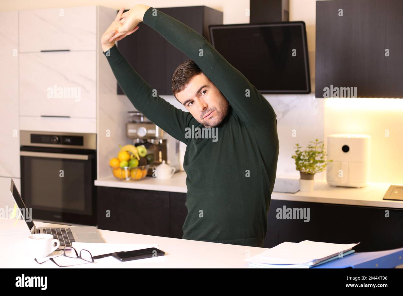 Uomo che si allunga in ufficio domestico Foto Stock