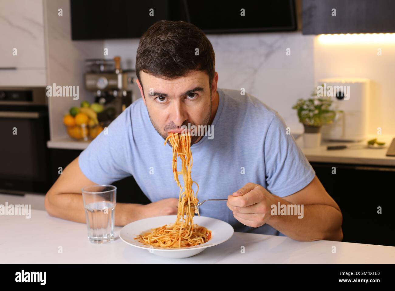 Uomo che mangia pasta con cattive maniere Foto Stock