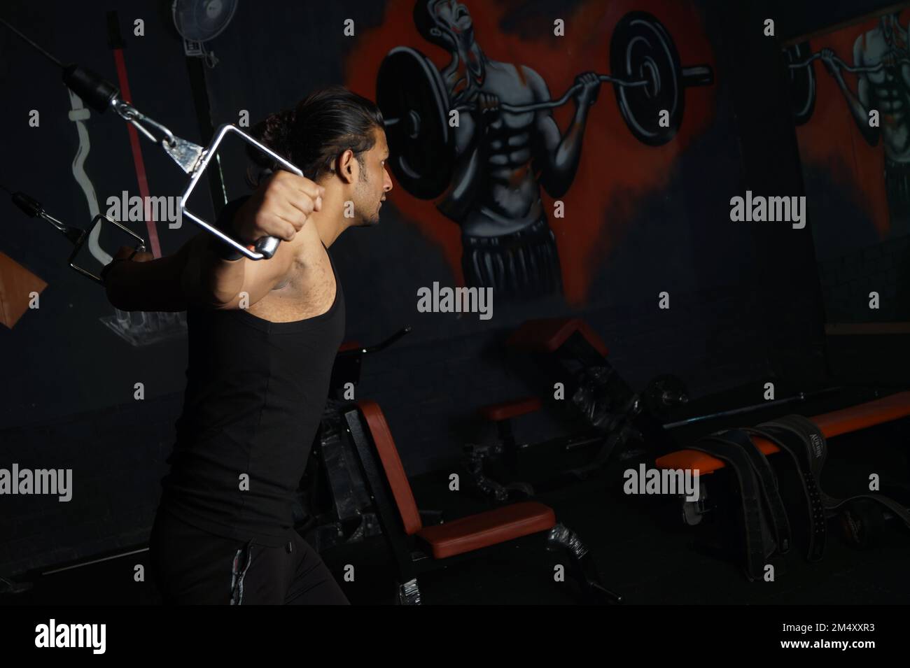 Un uomo del Sud asiatico che fa bicipiti in palestra Foto Stock