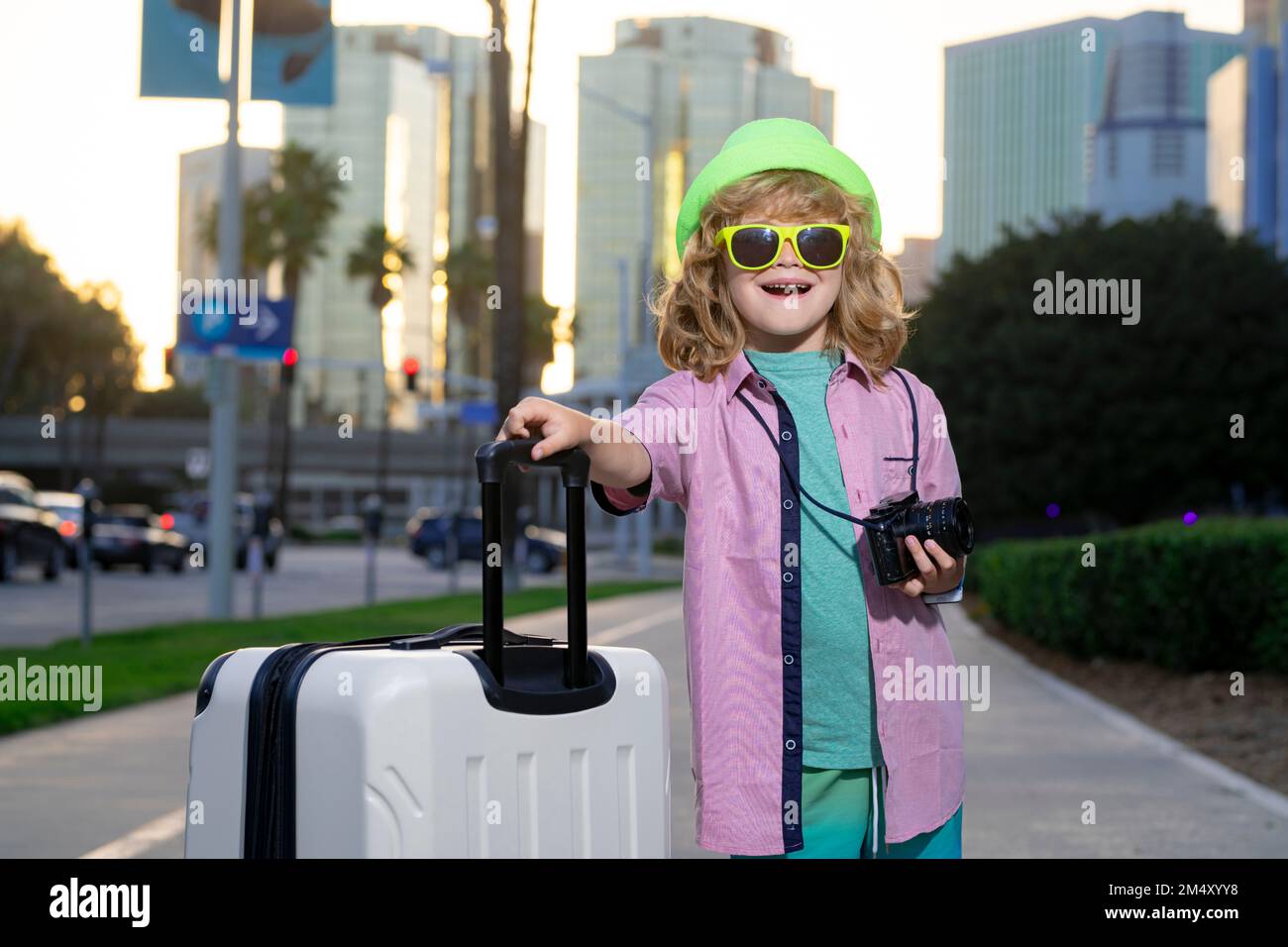 I bambini viaggiano. Felice bambino ragazzo che porta valigie da viaggio all'aperto sulla strada cittadina. Stile di vita di viaggio e sogni di viaggio. Foto Stock