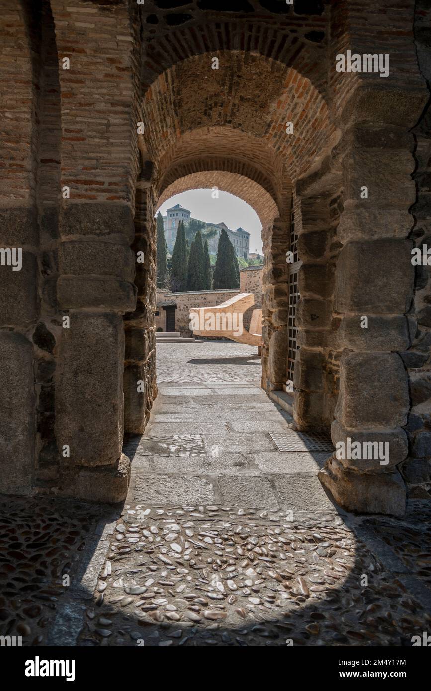 Raggi di sole che illuminano il pavimento di ciottoli di un ingresso in pietra nelle mura della monumentale città di Toledo, Spagna Foto Stock