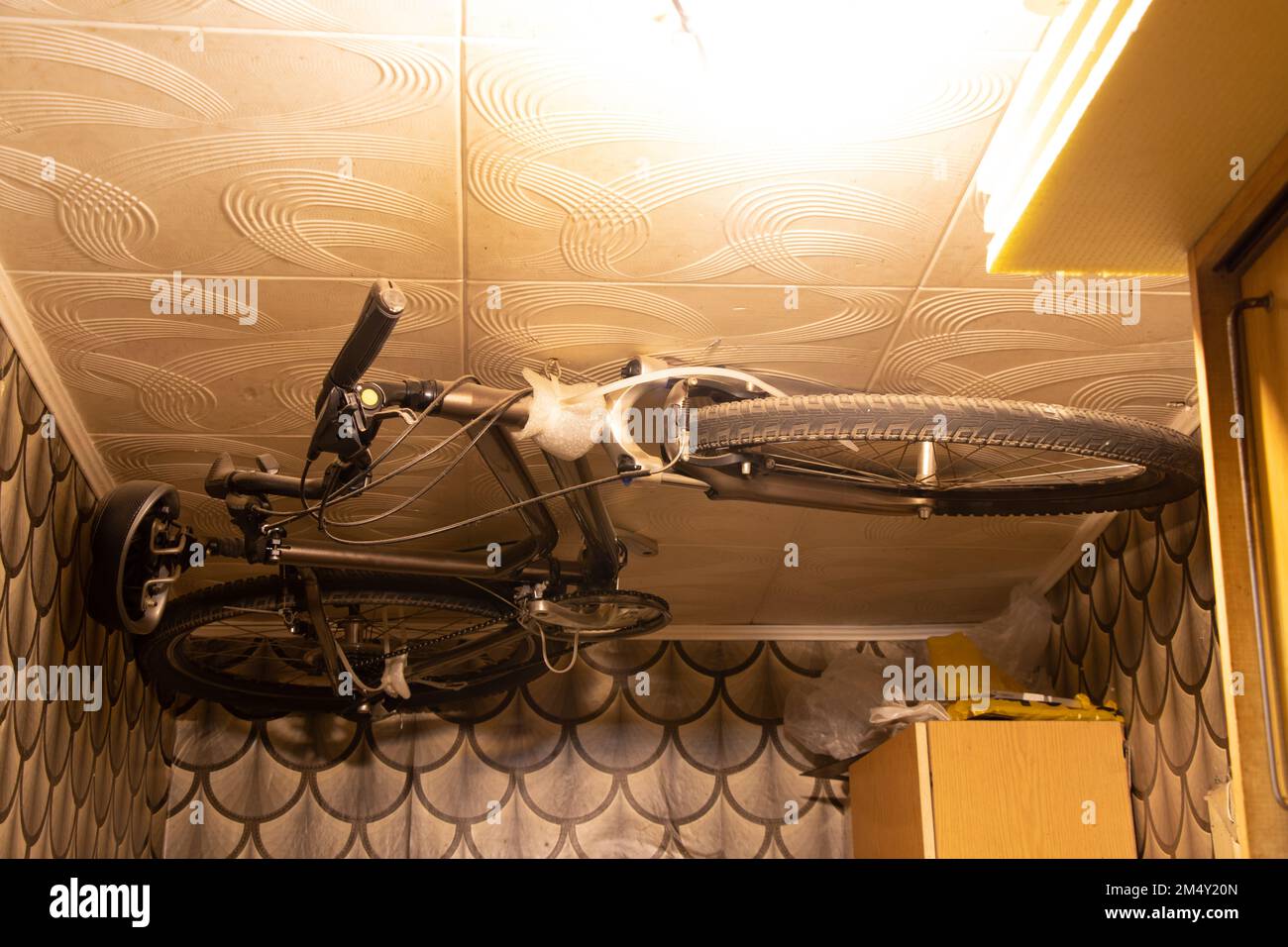 Bicicletta montata sul soffitto in un piccolo appartamento residenziale con spazio limitato, deposito biciclette a casa, idea Foto Stock