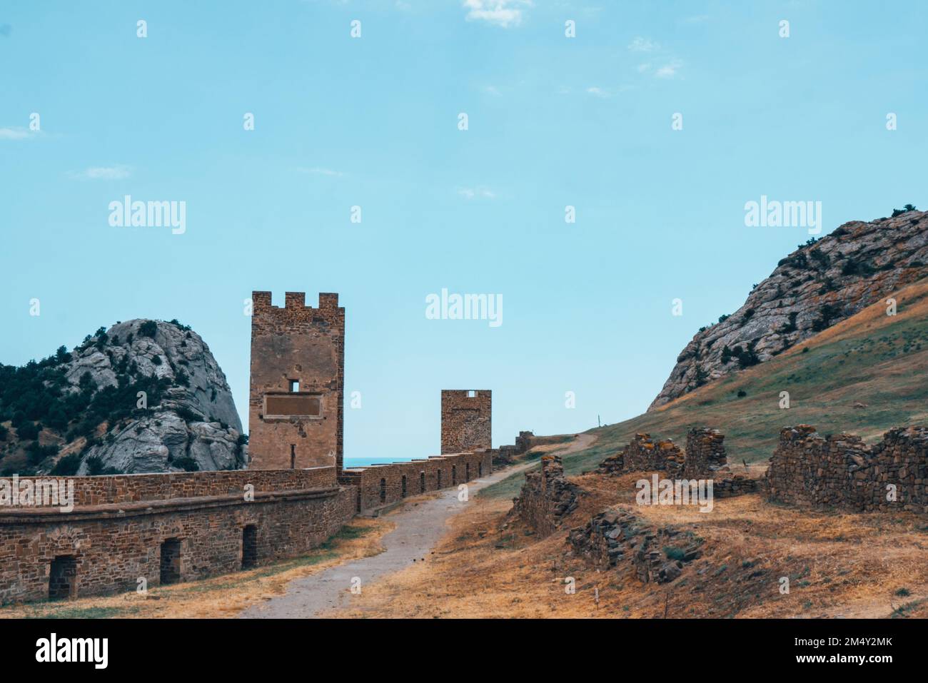 Una grande parete con una torre contro un cielo azzurro. Foto Stock