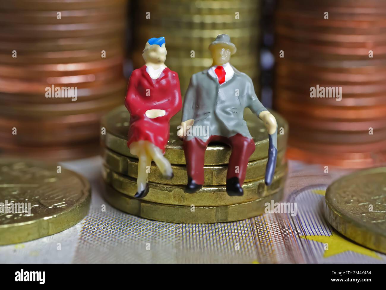 Abstract figure isolate di una coppia anziana in pensione seduta su una pila di monete in euro - concetto di pensione e risparmio pensionistico Foto Stock