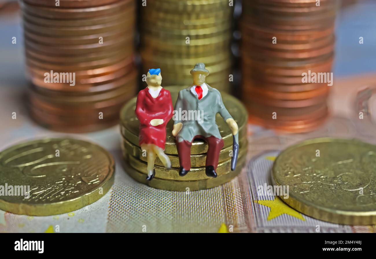 Abstract figure isolate di una coppia anziana in pensione seduta su una pila di monete in euro - concetto di pensione e risparmio pensionistico Foto Stock