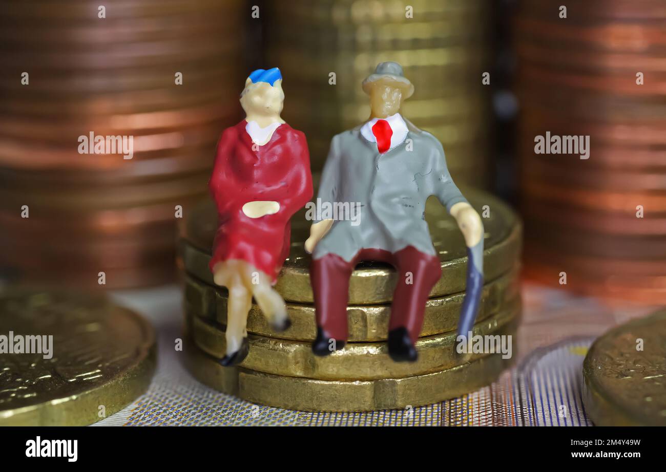 Abstract figure isolate di una coppia anziana in pensione seduta su una pila di monete in euro - concetto di pensione e risparmio pensionistico Foto Stock