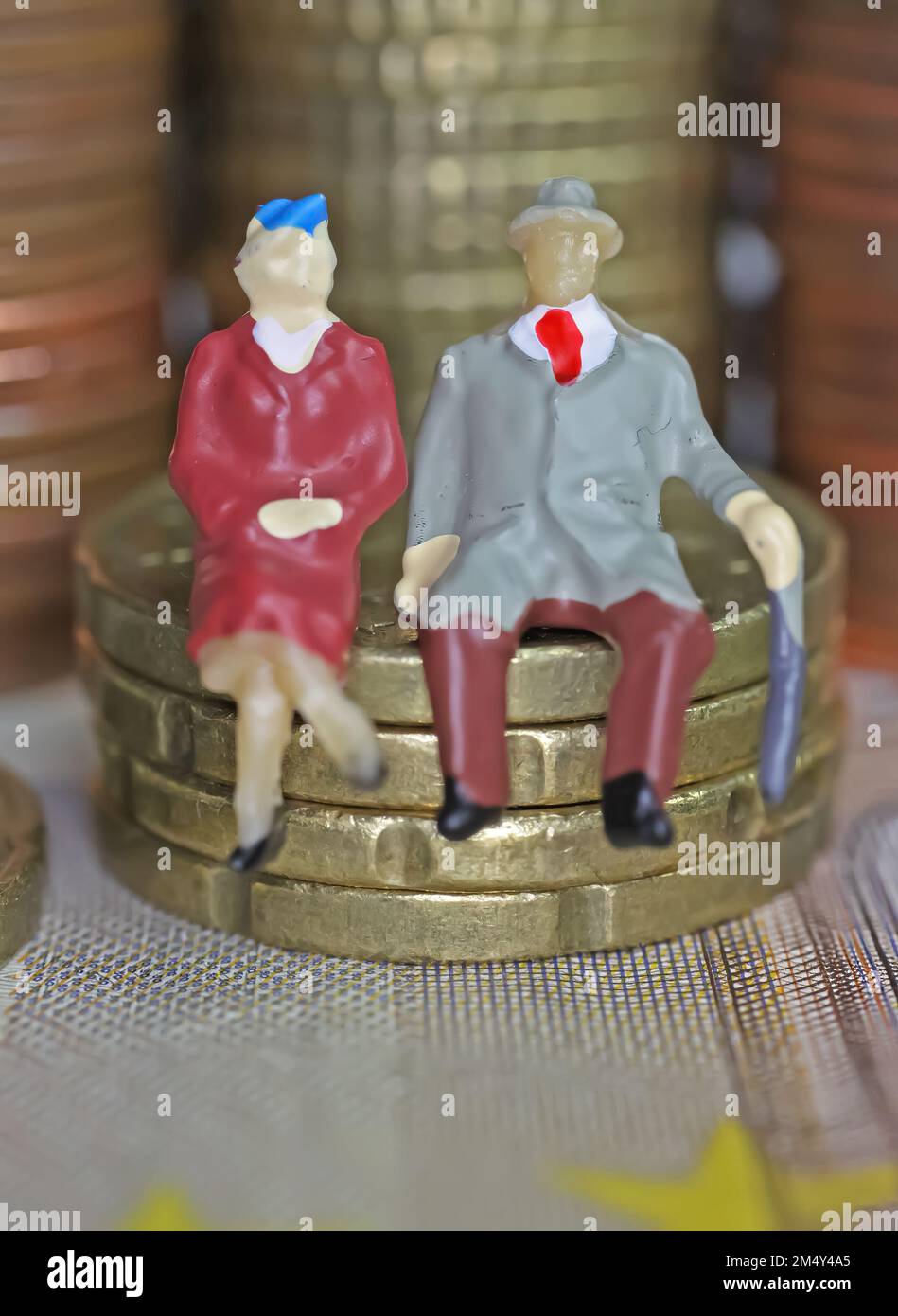 Abstract figure isolate di una coppia anziana in pensione seduta su una pila di monete in euro - concetto di pensione e risparmio pensionistico Foto Stock