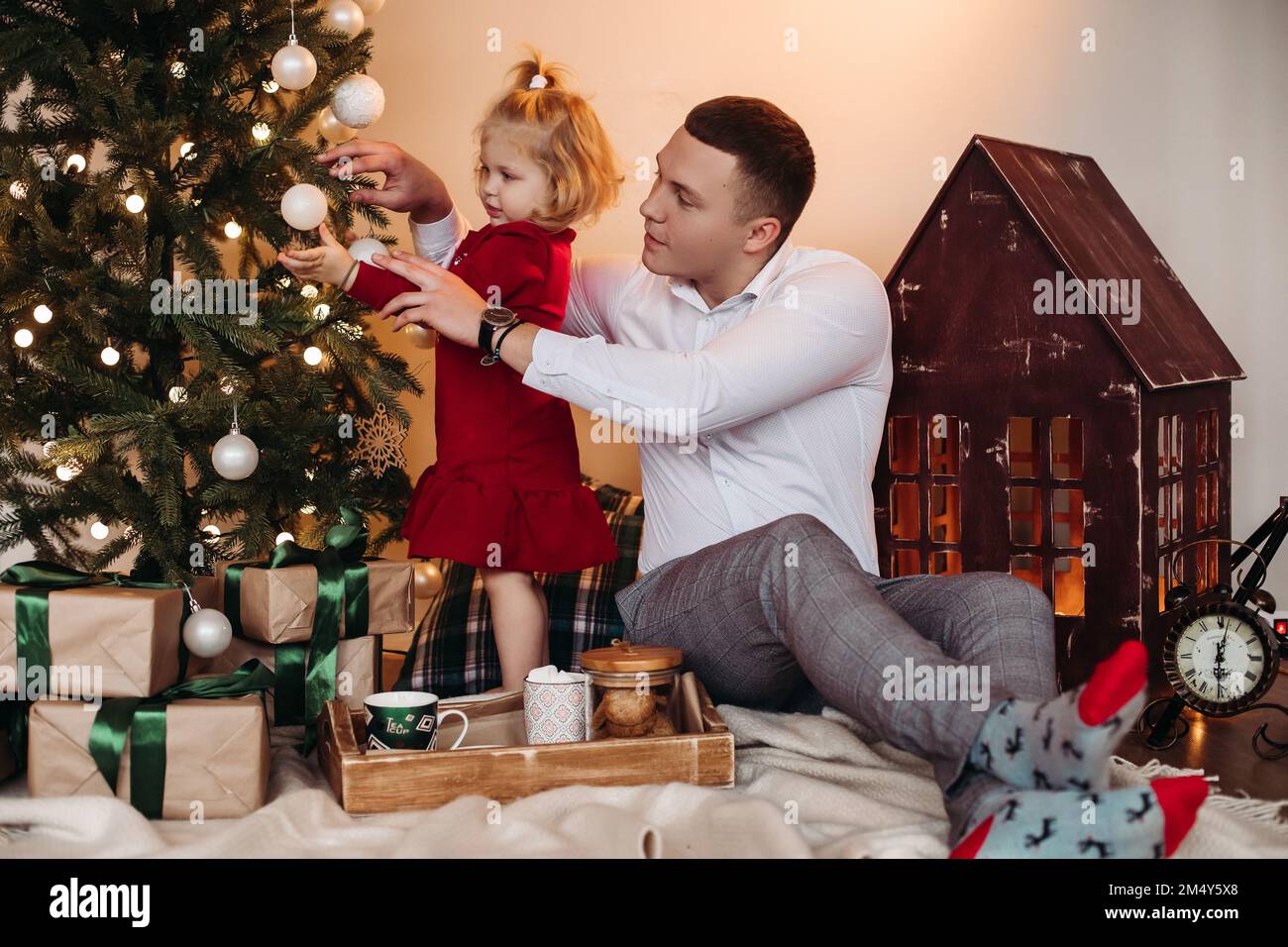 Gentiluomo disponibile e adorabile bambino che decora l'albero di Natale Foto Stock