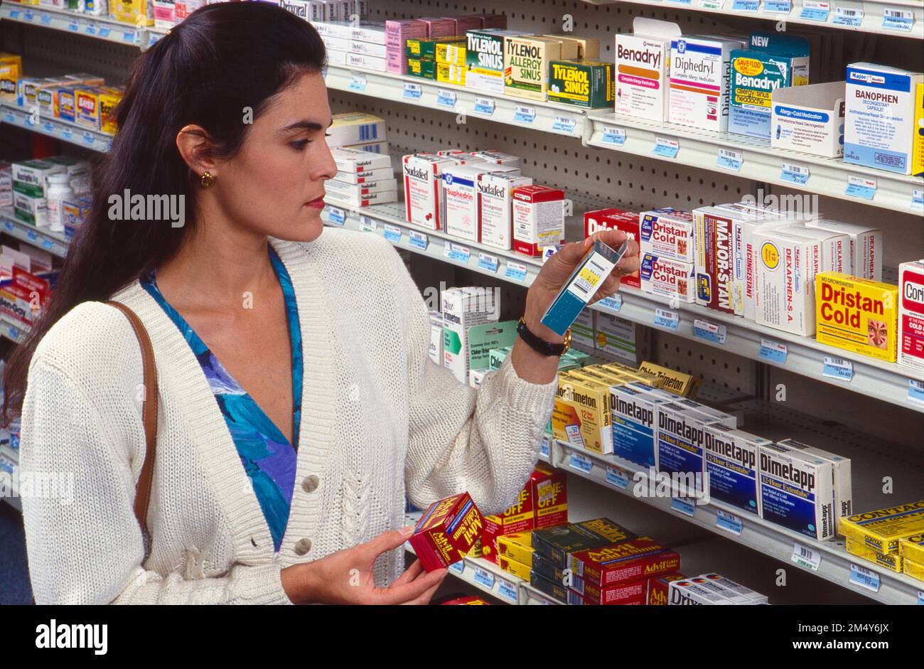 Giovane donna ispanica in una farmacia lettura etichette sui prodotti Foto Stock