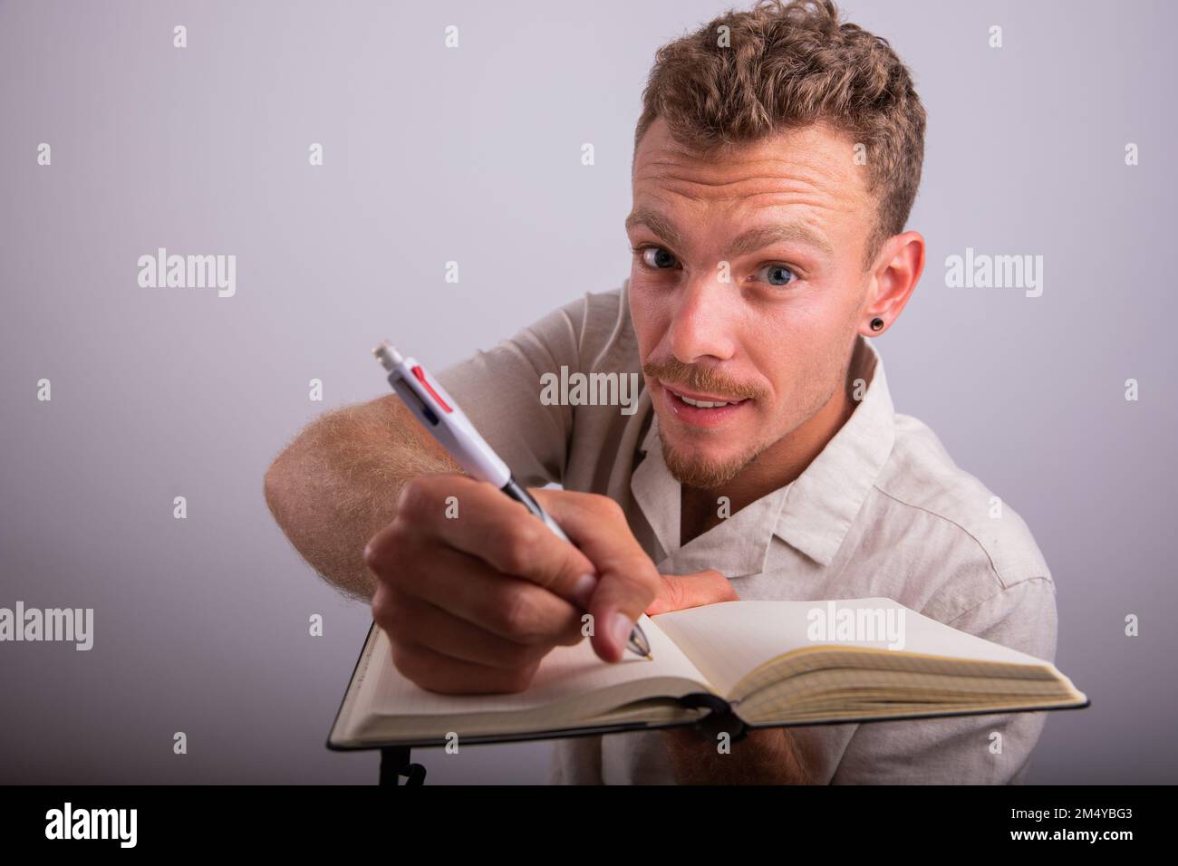 Uno scrittore sta tenendo una penna e la scrittura in un ordine del giorno, studio girato con uno sfondo bianco Foto Stock