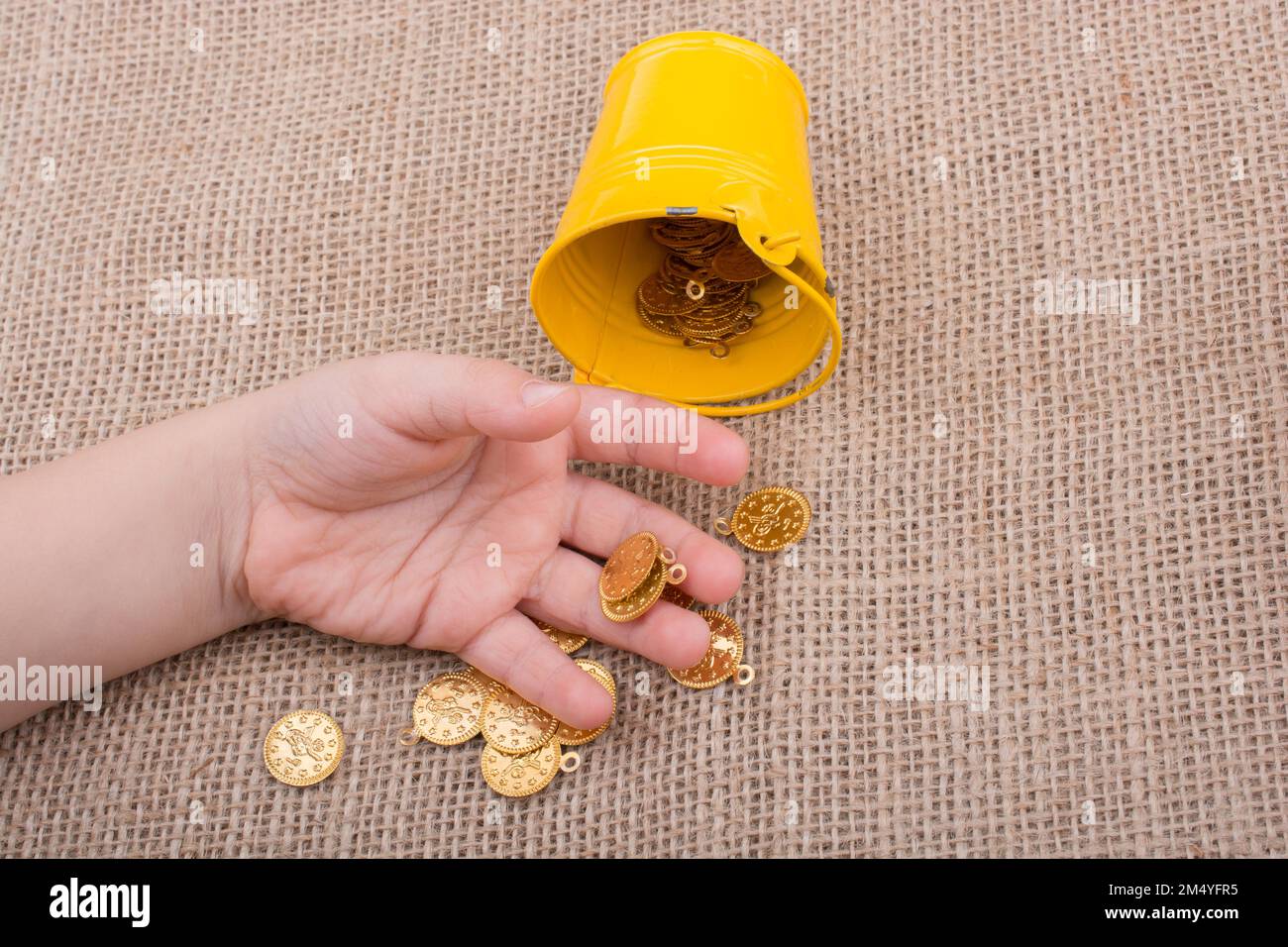 La benna e Falsificare monete d oro in mano su tela lo sfondo Foto Stock