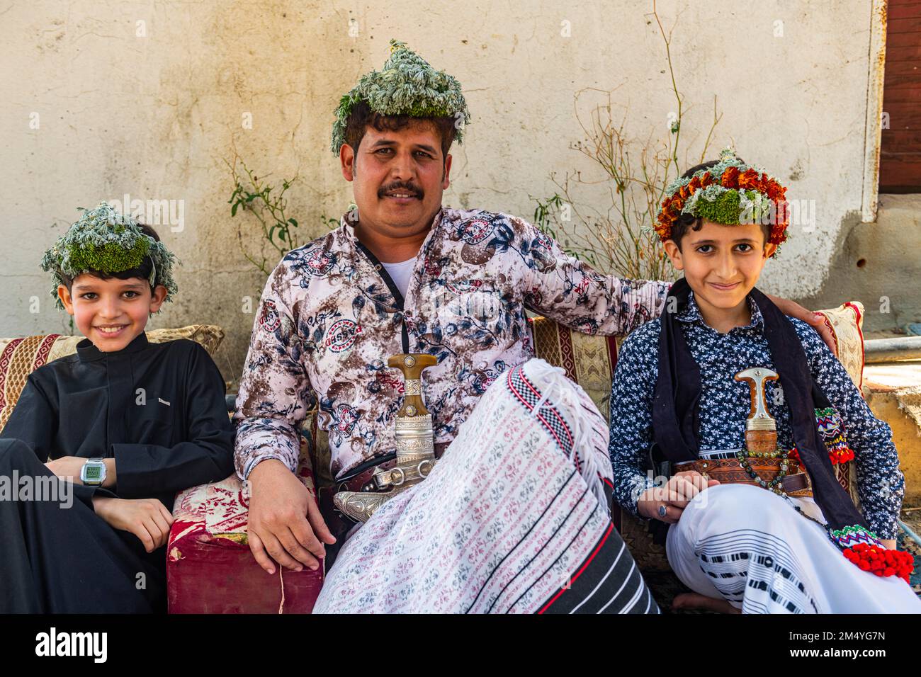 Uomo tradizionale vestito della tribù Qahtani Flower men, con i suoi figli, ASiR montagne, Regno di Arabia Saudita Foto Stock