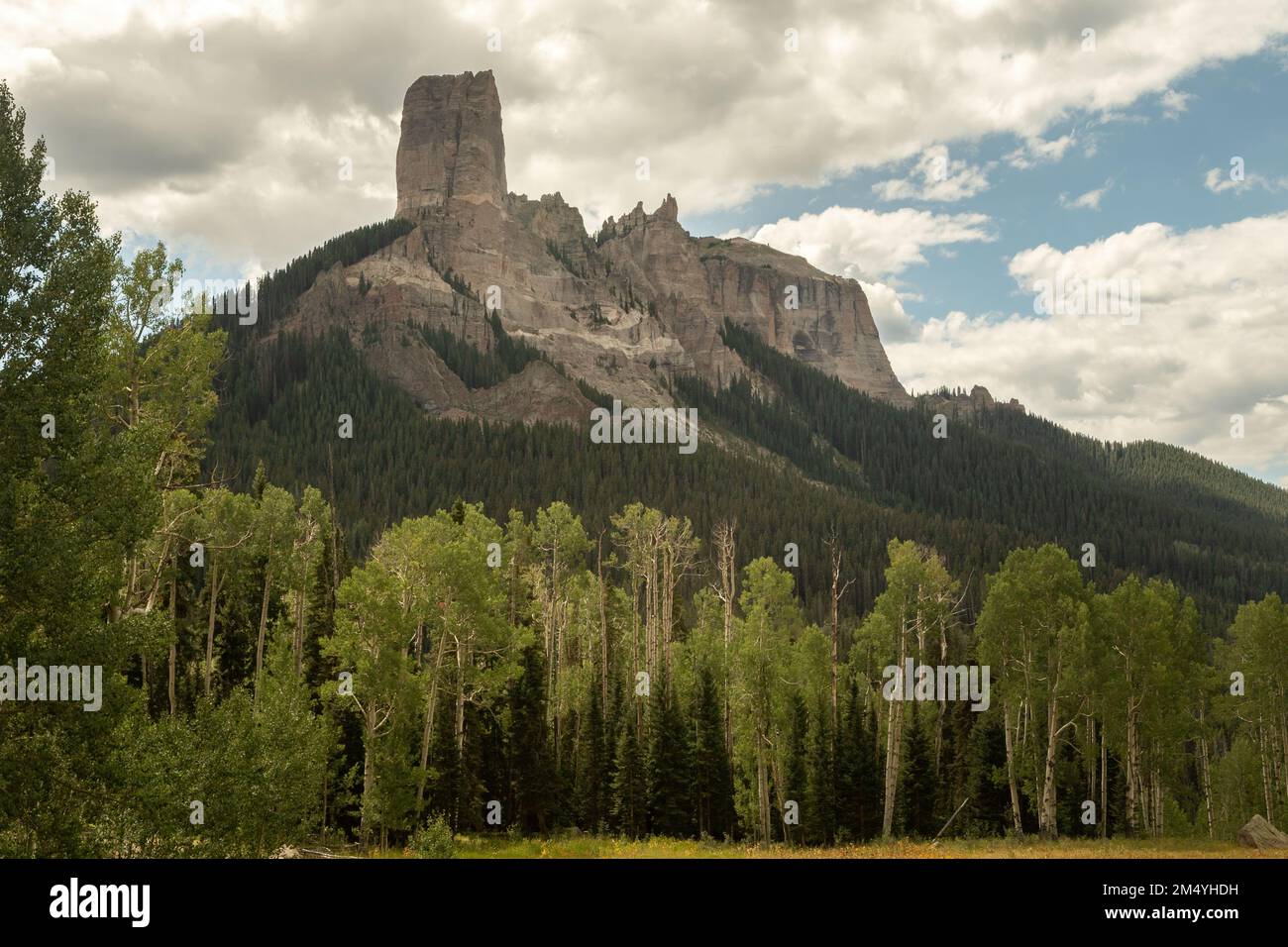 Chimney Rock e Courthouse Mountain lungo Owl Creek Pass, visto dietro un boschetto di aspens misti e sempreverdi vicino al Silver Jack Reservoir, Colorado. Foto Stock