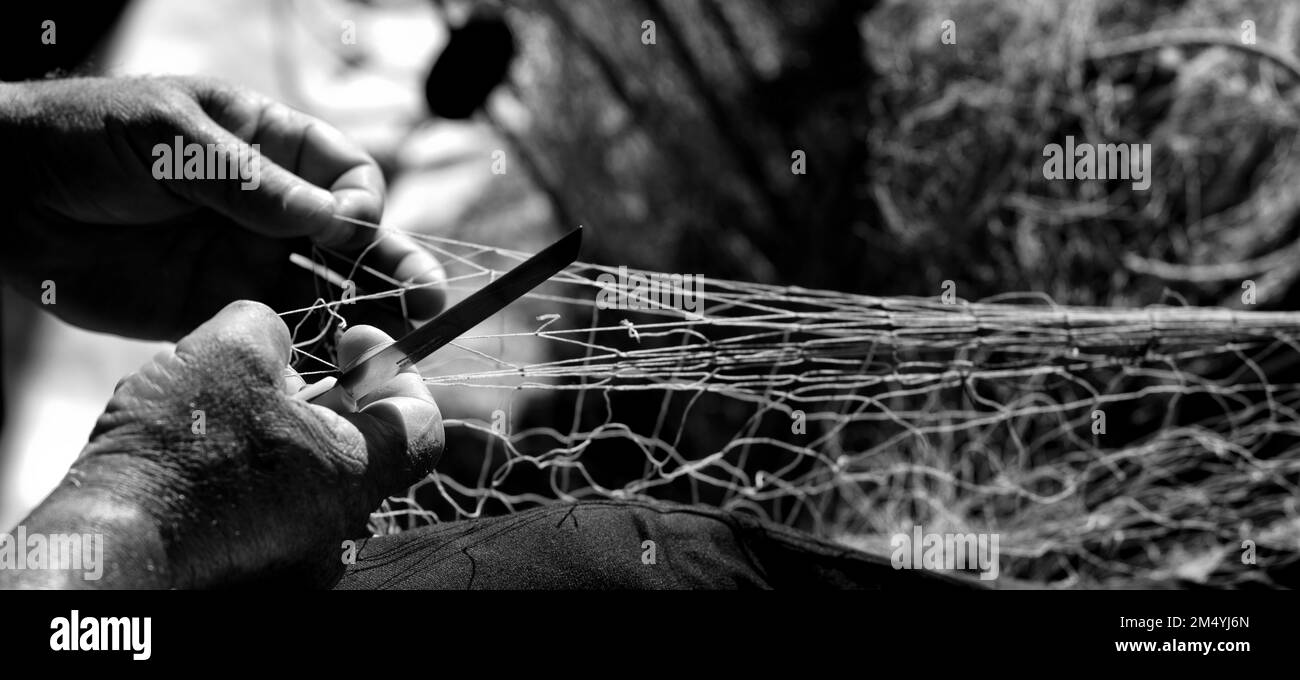 rete da pesca nelle mani di un pescatore, con ago e filo, fotografia in bianco e nero Foto Stock