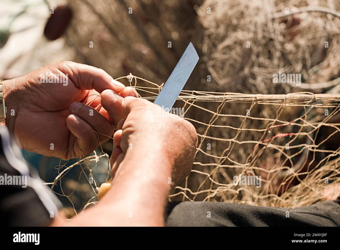 mani di pescatore con reti e coltello per la riparazione Foto Stock