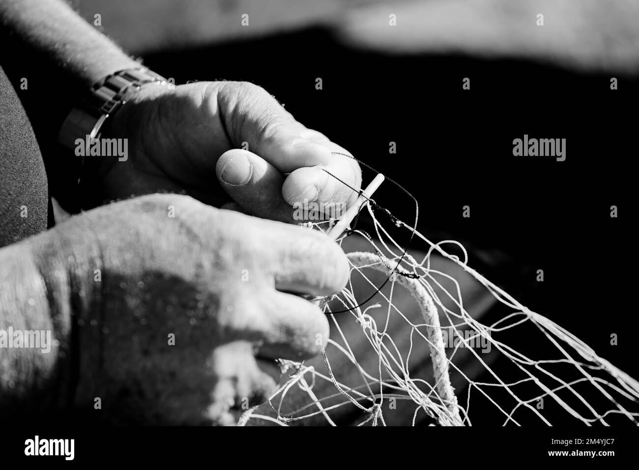 rete da pesca nelle mani di un pescatore, con ago e filo, fotografia in bianco e nero Foto Stock