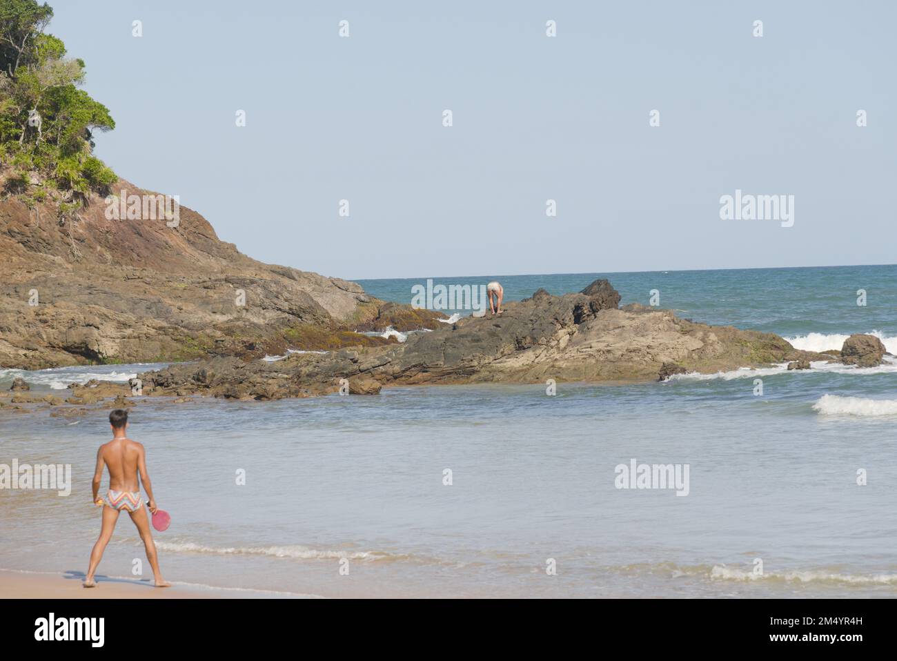 Bella vista panoramica di una spiaggia paradisiaca con rilievo roccioso in una giornata di sole con cielo blu, nuvole bianche e alcuni bagnanti Foto Stock
