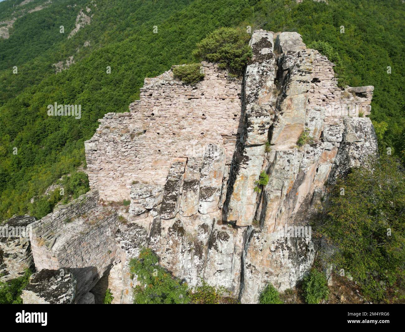 Una vista dall'alto di antiche rovine su una montagna boschiva Foto Stock
