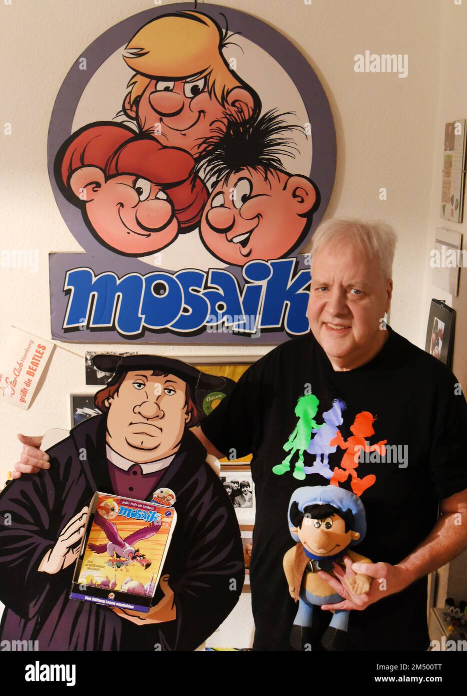 PRODUZIONE - 07 dicembre 2022, Sassonia, Lipsia: Il collezionista Thomas Wilde si trova nel suo appartamento con le mostre dei tre personaggi simili a goblin Abrax, Brabax e Califax della rivista comica Mosaik, una mostra di Luther (l) della serie con lo stesso nome e la bambola Dig dei Digedags in mano. Gli Abrafax sono i successori dei Digedag dei fumetti Mosaik, che sono stati i principali eroi della rivista di fumetti Mosaik pubblicata nella RDT dal 1955 al 1975 e appartengono ad una stima di 8.000 oggetti Mosaik raccolti dall'ex insegnante inglese e tedesco di 63 anni. Nel suo appartamento Foto Stock
