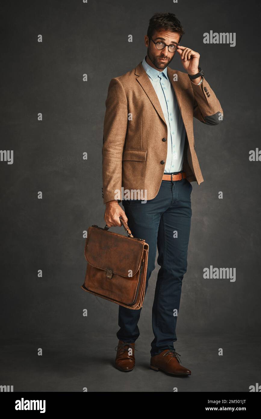 Elegante e funzionale. Studio di un bel giovane uomo che si posa su uno sfondo grigio. Foto Stock