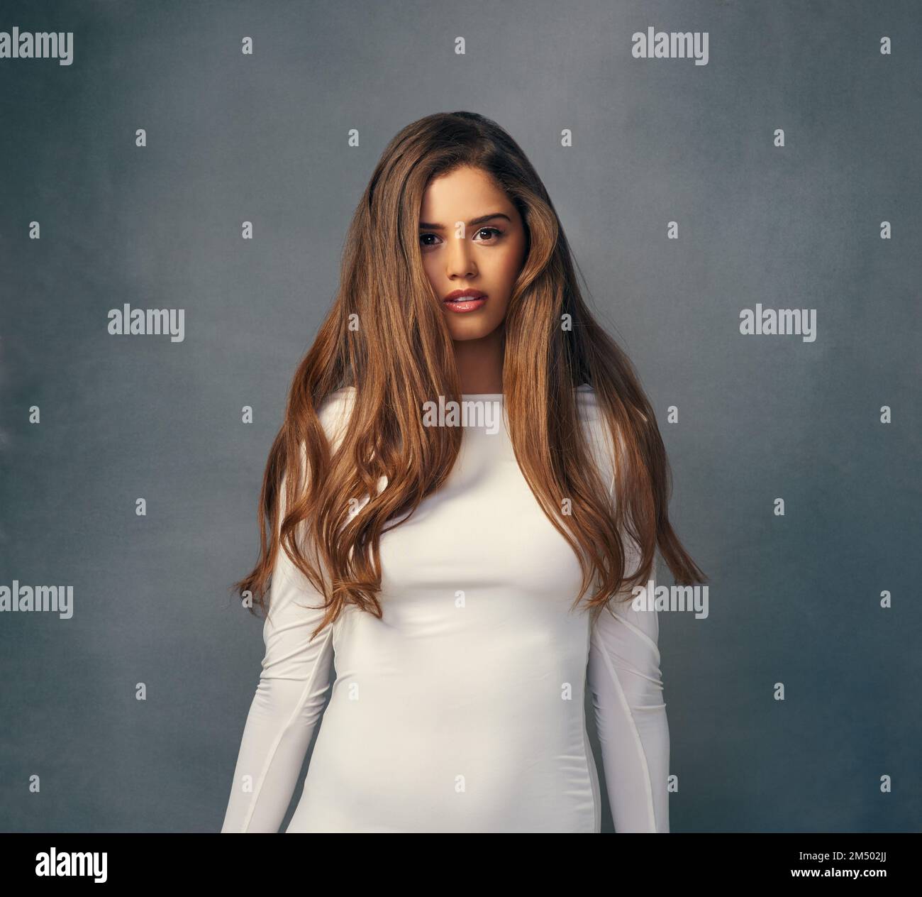 Non ho idea che cosa un giorno difettoso dei capelli assomigli. Studio ritratto di una giovane donna attraente posa su uno sfondo grigio. Foto Stock