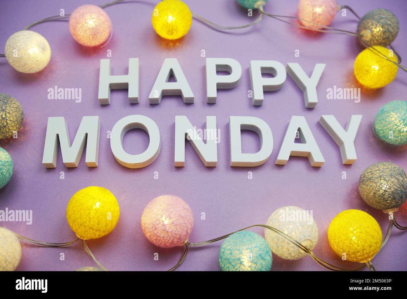 Lettere dell'alfabeto del lunedì felice con palle di cotone a LED su sfondo viola Foto Stock