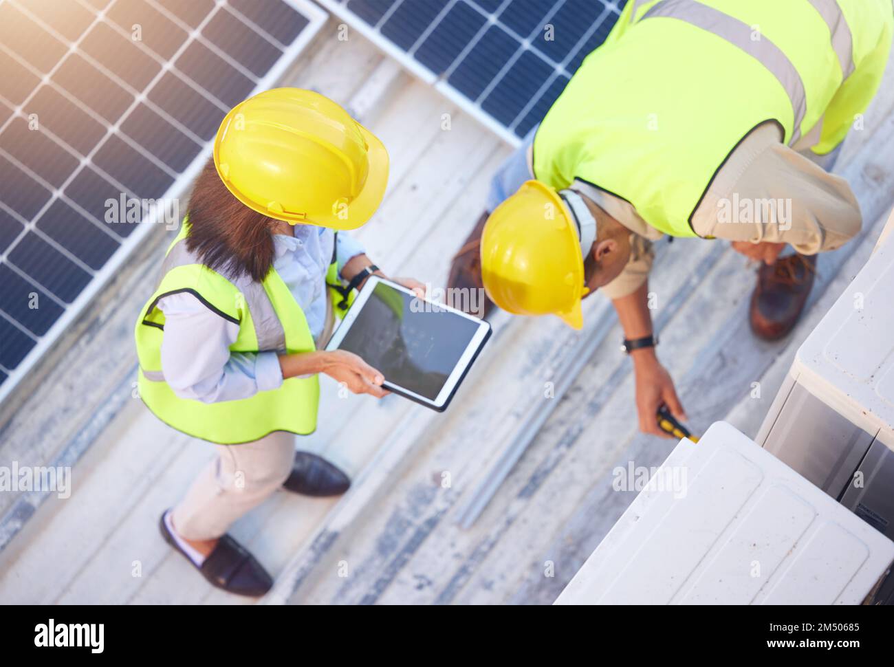 Vista dall'alto, lavoro di squadra e ingegneri con tablet sul tetto solare per manutenzione, ispezione o installazione. Energia solare, energia rinnovabile e uomo e. Foto Stock