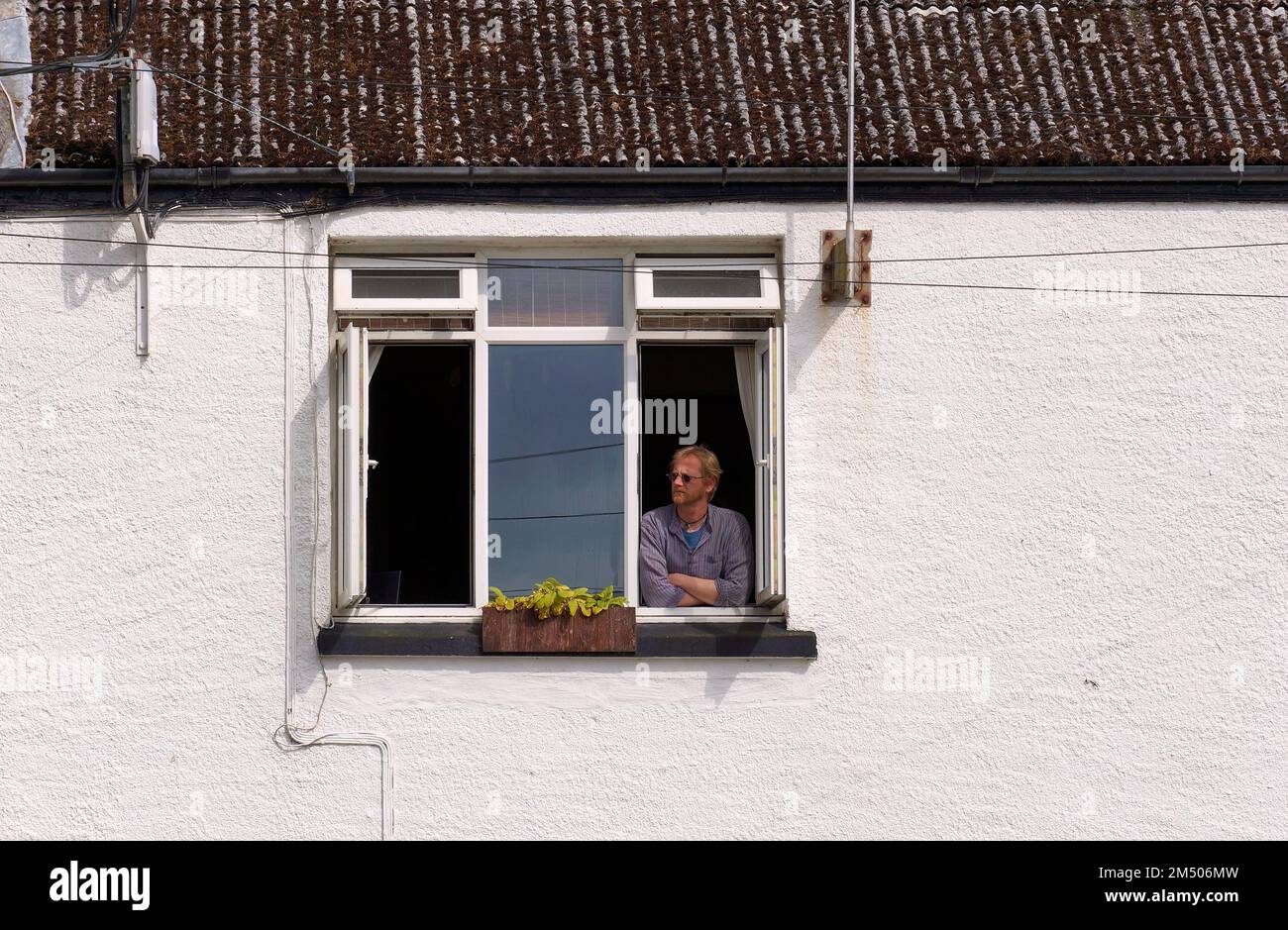 Uomo rilassato che guarda fuori dalla finestra di una casa Foto Stock