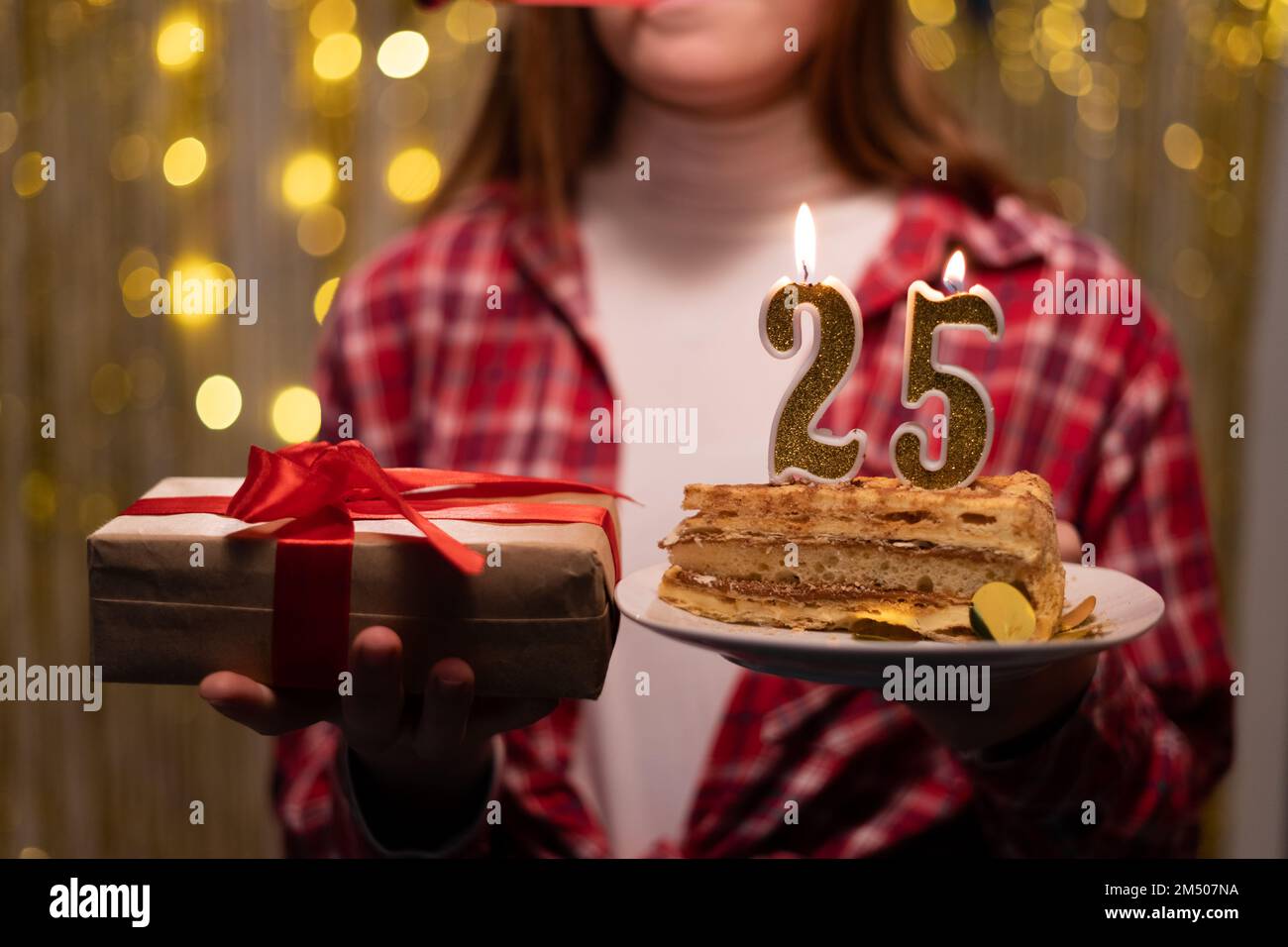 Festa di compleanno. Giovane donna con regalo e torta di compleanno con candele numero 25. Festa di compleanno a casa. Spazio di copia Foto Stock