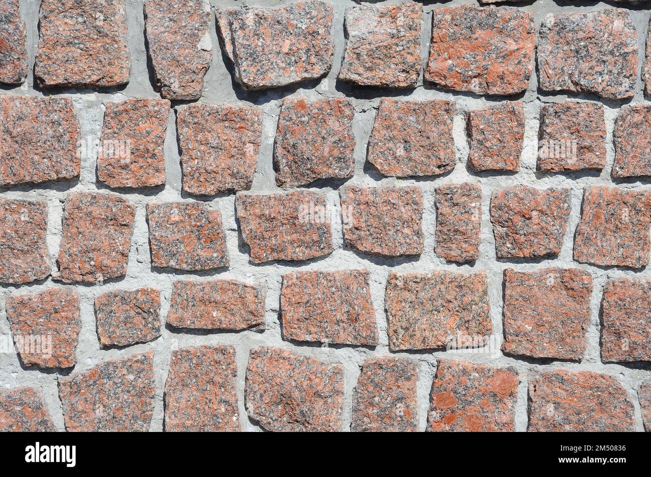 La struttura di un muro fatto di pietre di granito rosso. Pietre tagliate in file. Foto Stock