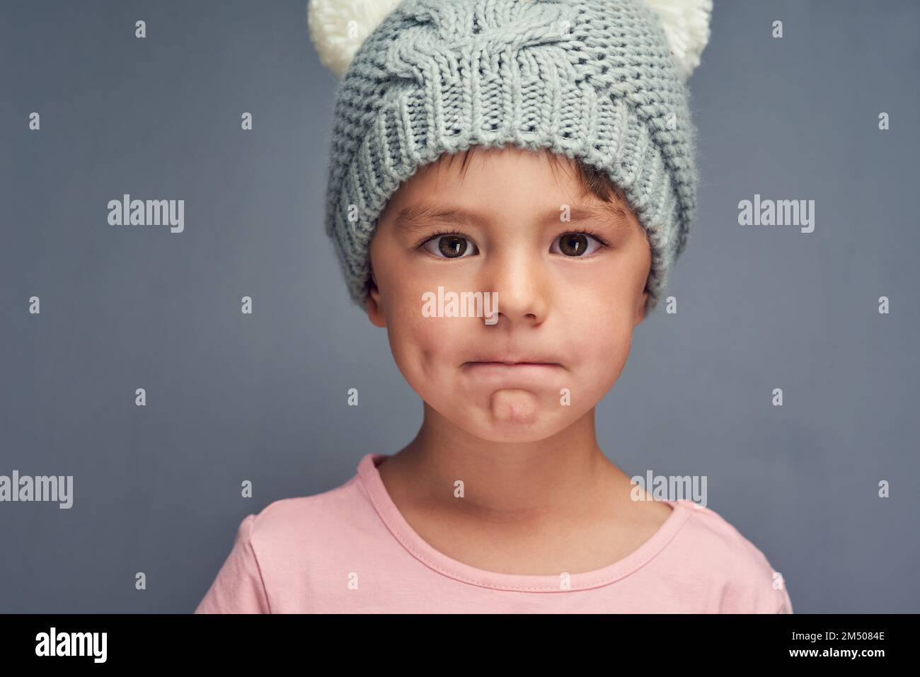 La mia concavità mi fa sembrare carino. Studio ritratto di un adorabile ragazzino che si posa su uno sfondo grigio. Foto Stock