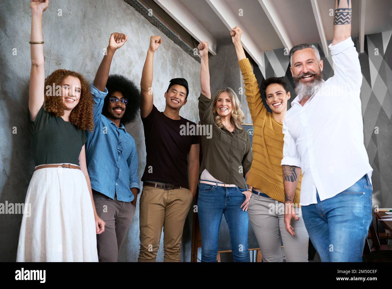 L'abbiamo fatto al top. Ritratto ritagliato di un gruppo di designer che alzano i pugni in un ufficio creativo. Foto Stock