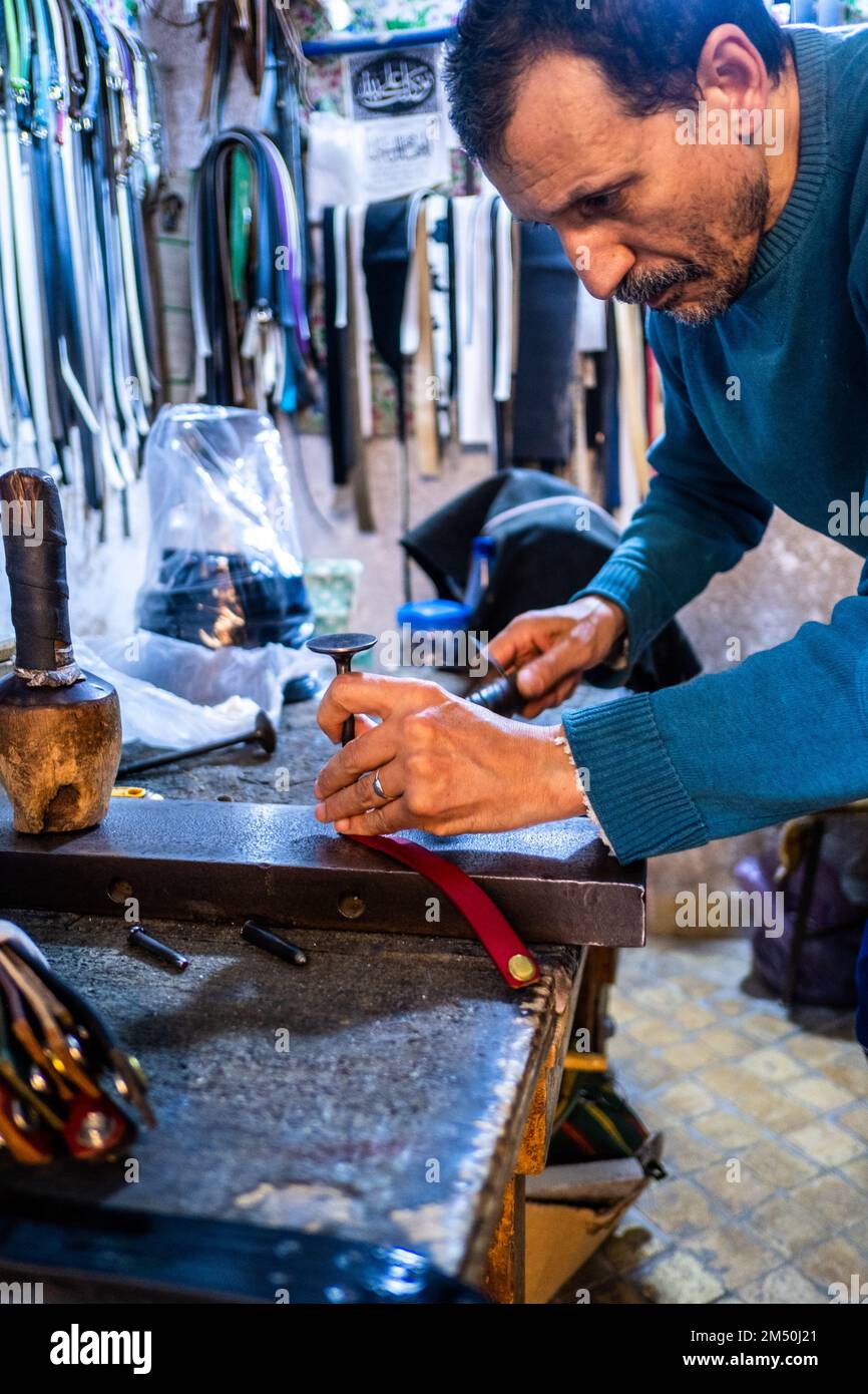 Fes, Marocco; 7th dicembre 2022: Un artigiano del cuoio lavora nel suo laboratorio nella medina. La pelle Fes è nota per la sua alta qualità e morbidezza. Foto Stock