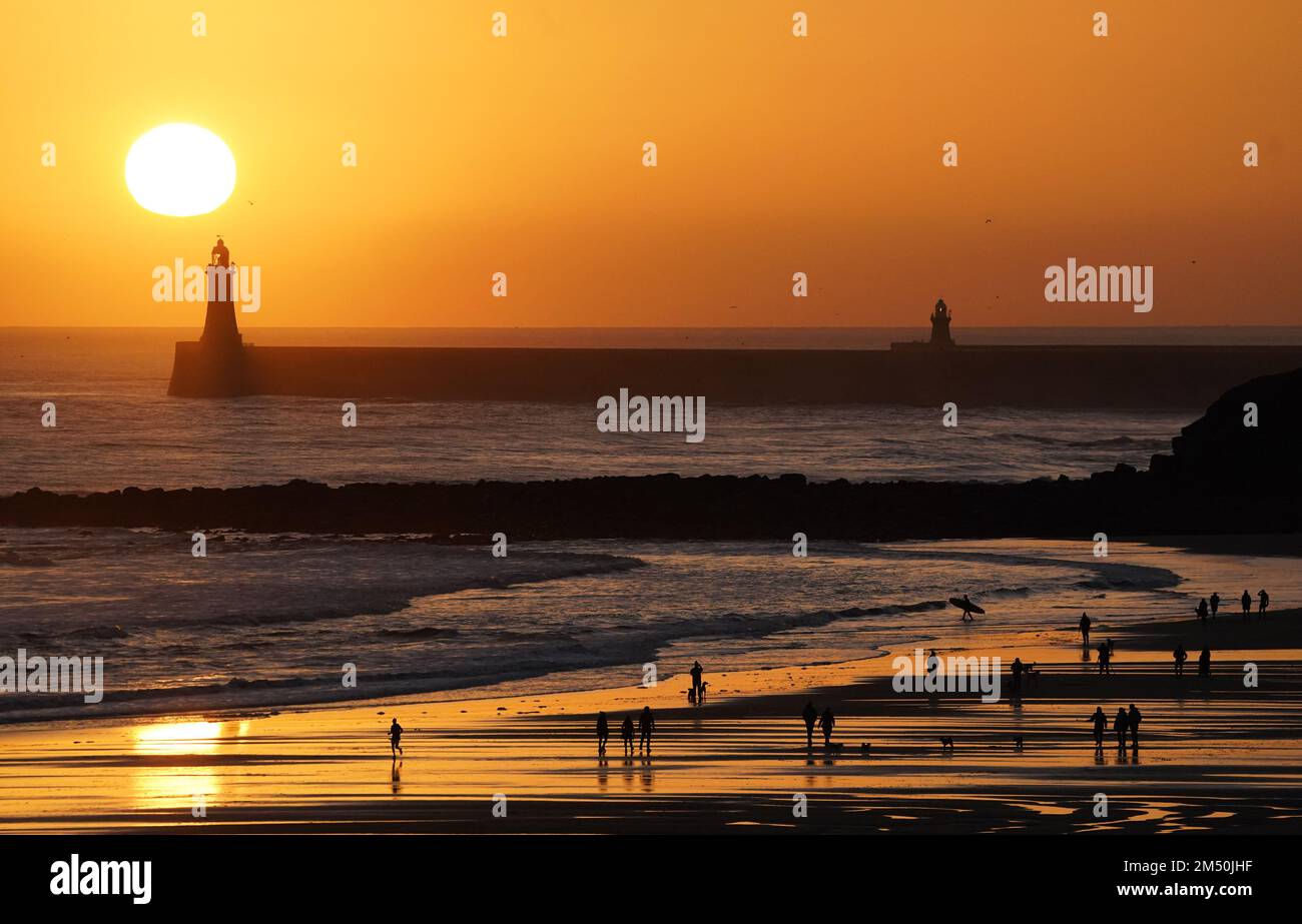 La gente gode di una passeggiata della vigilia di Natale all'alba sulla spiaggia di Tynemouth Longsands nel Nord Est dell'Inghilterra. Data immagine: Sabato 24 dicembre 2022. Foto Stock