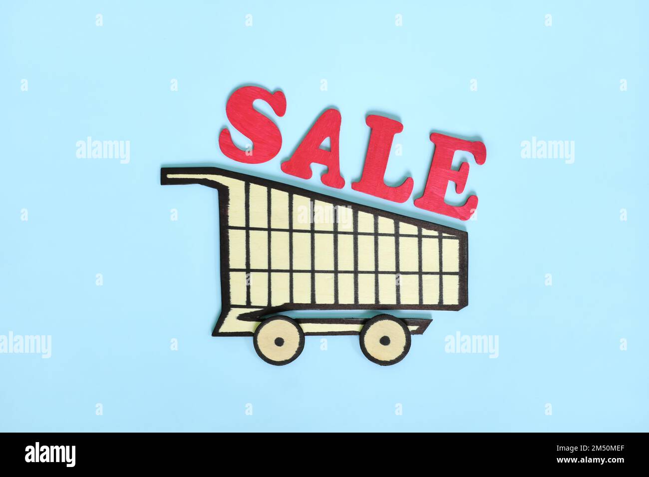 Concetto di vendita di shopping. Carrello in legno con vendita di parola su sfondo blu. Foto Stock