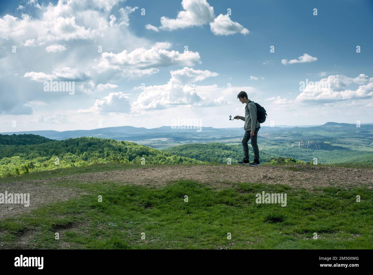 Giovane uomo che filma con il telefono cellulare su un grip che cammina sul sentiero Foto Stock
