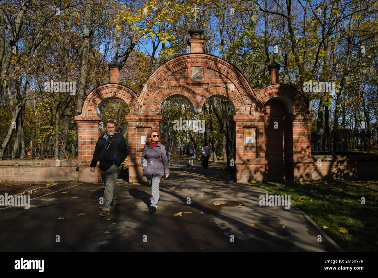 Uomo e donna camminano attraverso un cancello della chiesa nel Museo-Riserva di Kolomenskoye in una giornata di sole autunno. Mosca, Russia. Foto Stock