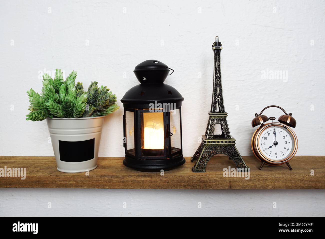 Statua della Torre Eiffel e lanterna nera con lampada a LED a candela e  sveglia su scaffali di legno Foto stock - Alamy